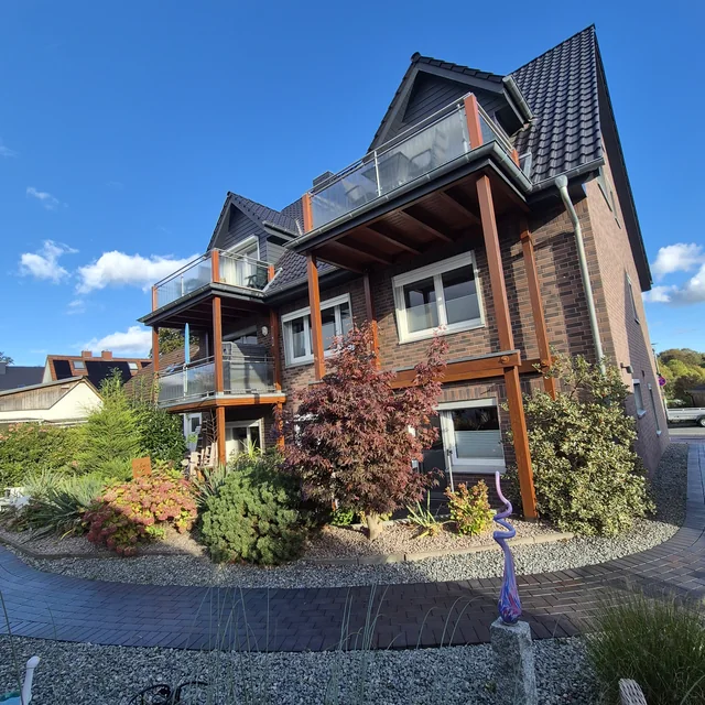 Haus Passat mit Balkonen und bepflanztem Garten, seitlich gesehen